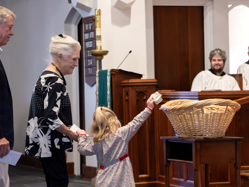 Child placing offering in basket during church service at Good Shepherd Episcopal Church in Austin