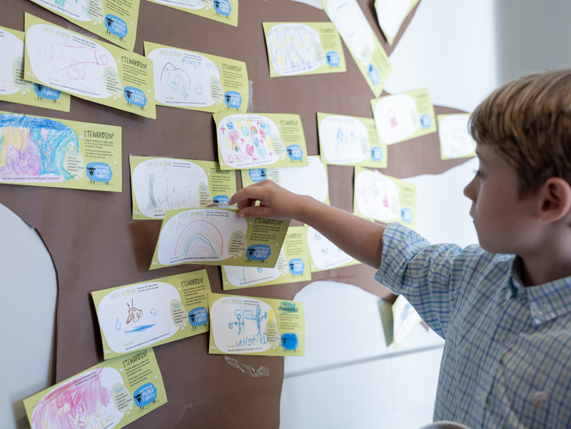 Child placing stewardship pledge card on display board at Good Shepherd Episcopal Church in Austin