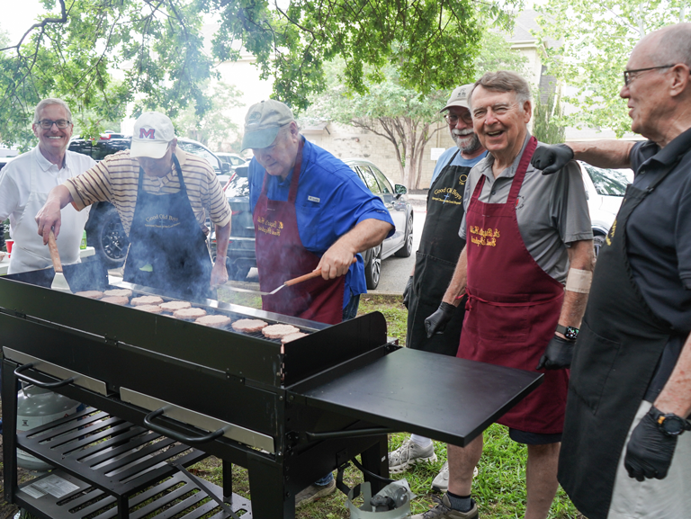 Good Shepherd Episcopal Church volunteers grilling burgers outdoors for community meal in Austin Texas