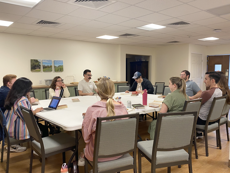 Young adults gather around a table with Bibles for a 20s & 30s Bible Study at Good Shepherd Episcopal Church in Austin, Texas.